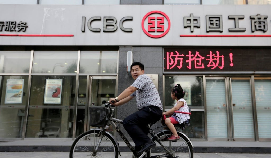 A man and his daughter ride past a branch of the Industrial and Commercial Bank of China in Beijing. Photo: Reuters
