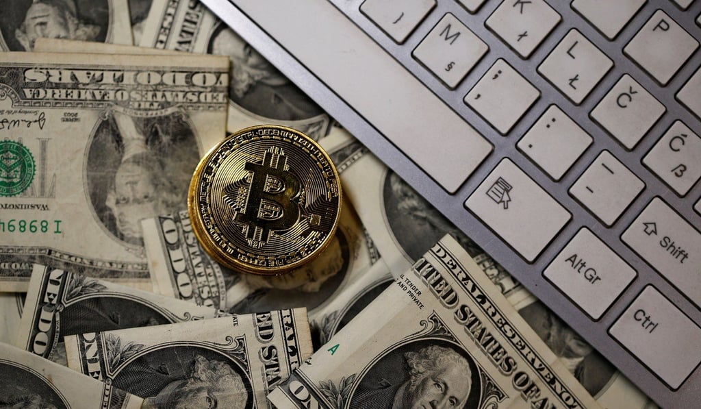 A bitcoin is placed on US dollar banknotes next to computer keyboard. Photo: Reuters