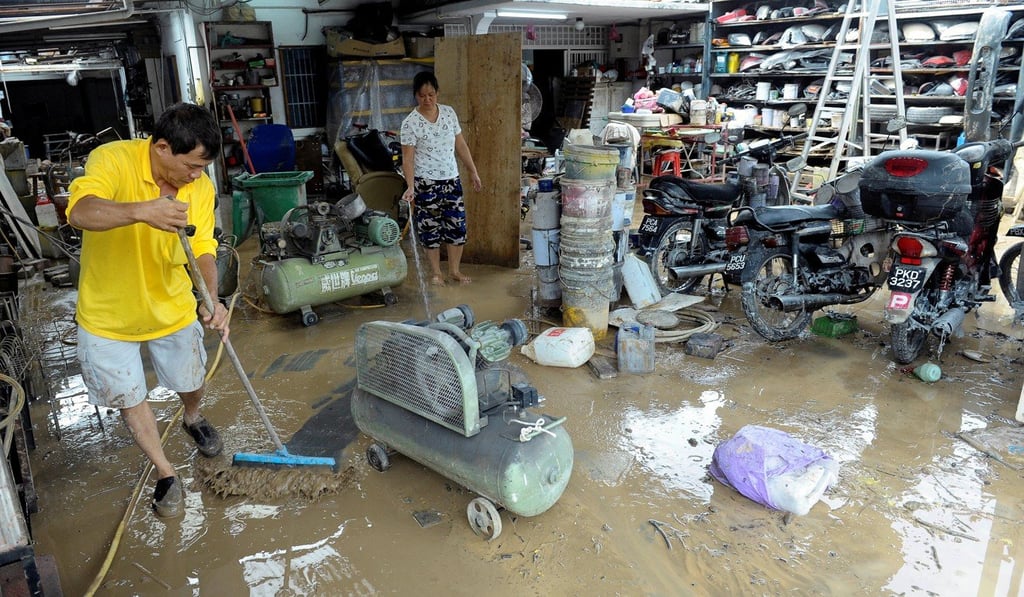 A Malaysian shop owner cleans up after a flood in George Town, Penang. Photo: Reuters