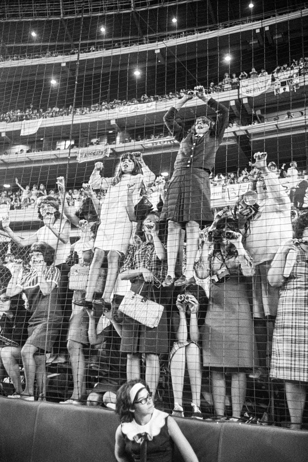 Young fans climb a fence to see The Beatles better during the concert at Shea Stadium.