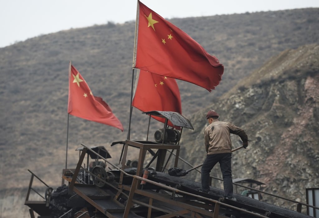 In this photo taken on November 20, 2015, a worker clears a conveyor belt used to transport coal near a mine at Datong in Shanxi province. Photo: AFP