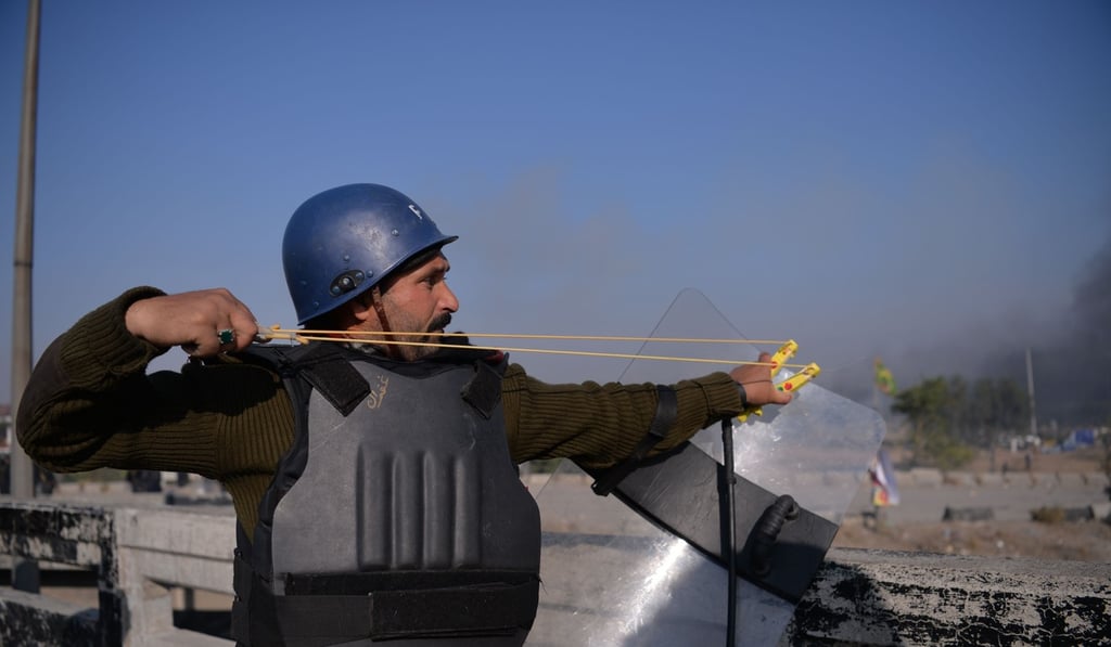 A Pakistani policeman uses a slingshot during clashes. Photo: AFP