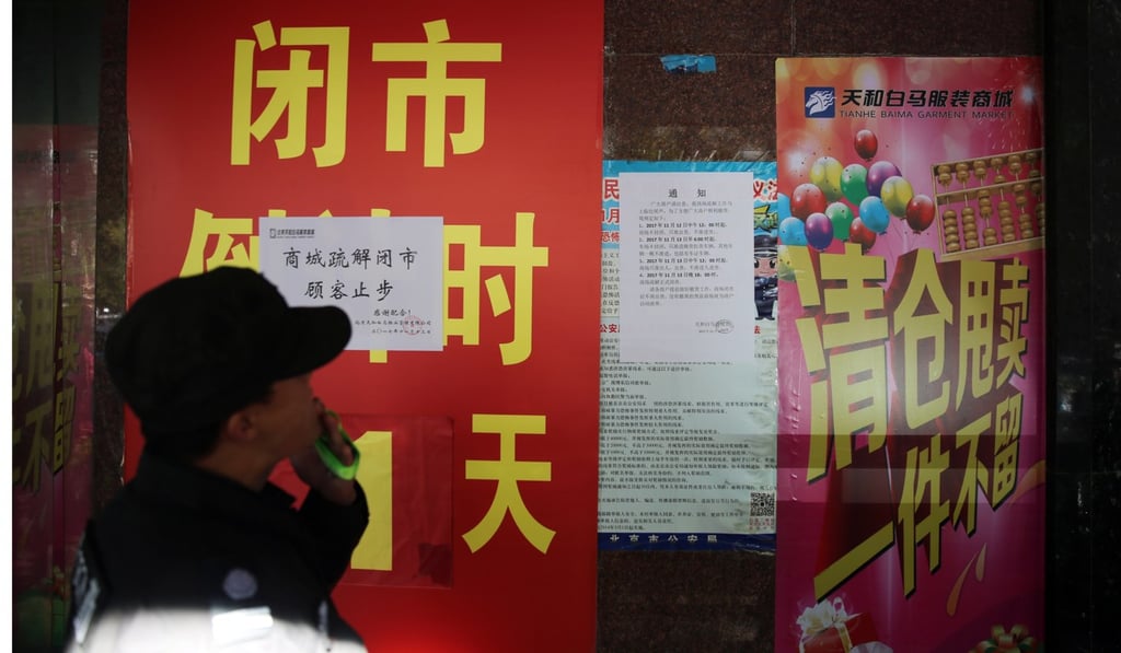 A Chinese security guard stands next to posters saying a clothes wholesale market has been shut down as the authorities crackdown on migrant workers living in the city without authorisation. Photo: EPA A Chinese security guard stands next to posters saying a clothes wholesale market has been shut down as the authorities crackdown on migrant workers living in the city without authorisation. Photo: EPA