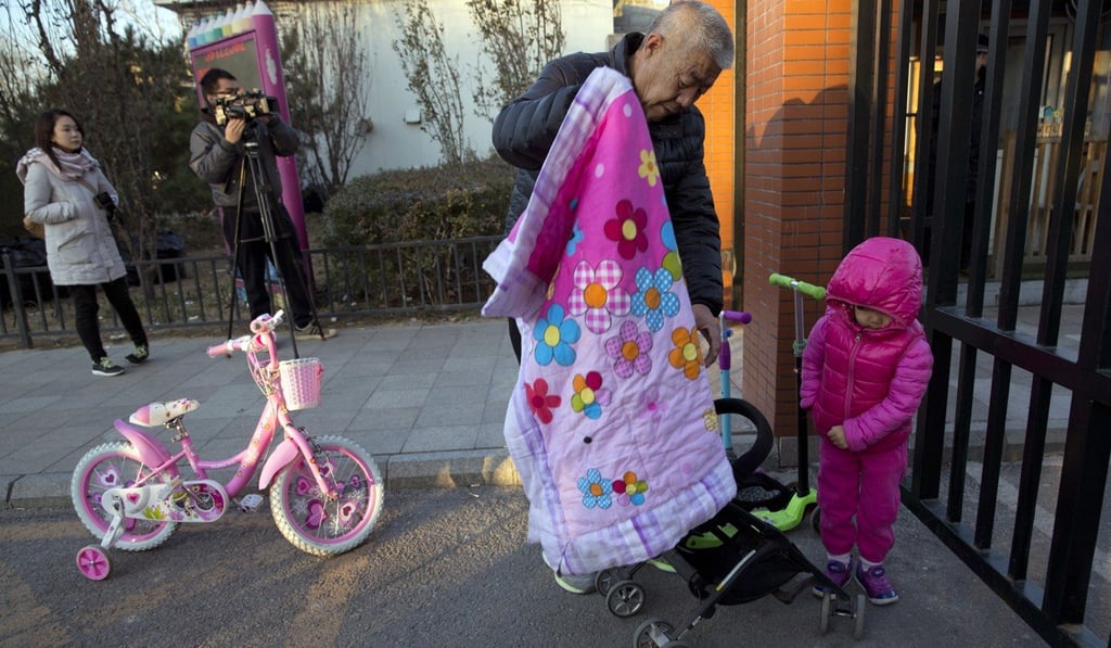 An elderly man escorts a child to the RYB kindergarten in Beijing, China.