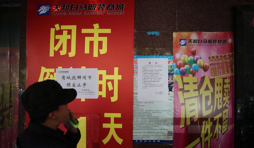 A Chinese security guard reads posters saying a clothes market has been closed due to Beijing's new urban planning policy. The drive is seen by many as an attempt to force lower-income residents out of the city. Photo: EPA