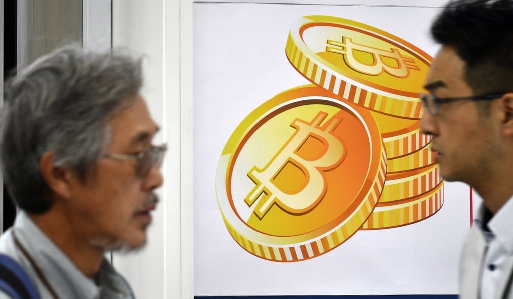 Pedestrians walk past a bitcoin currency poster at the entrance of a Bic Camera electronics retailers store in central Tokyo, Japan. Photo: EPA-EFE Pedestrians walk past a bitcoin currency poster at the entrance of a Bic Camera electronics retailers store in central Tokyo, Japan. Photo: EPA-EFE