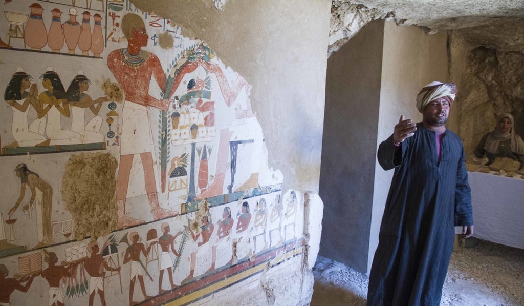 An Egyptian guard stands next to a funeral mural inside a newly discovered tomb on Luxor's west bank known as