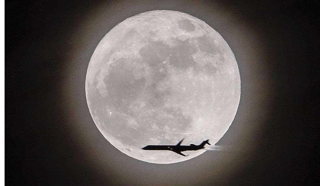 An aeroplane crosses in front of the moon. Photo: EPA