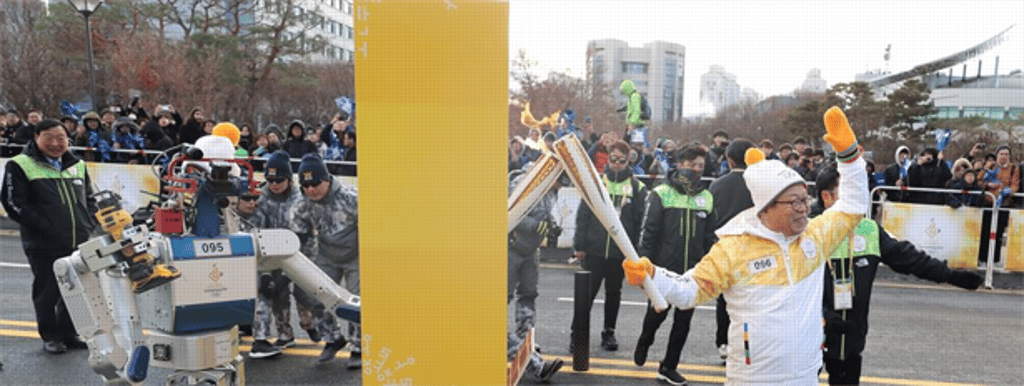 HUBO passes the flame to Professor Oh Jun-ho, after breaking the wall in Daejeon. Photo: Yonhap HUBO passes the flame to Professor Oh Jun-ho, after breaking the wall in Daejeon. Photo: Yonhap