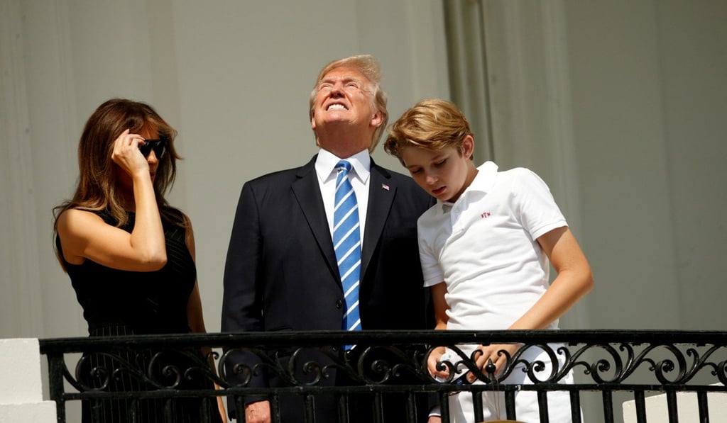 Without his protective glasses on, US President Donald Trump looks up towards the solar eclipse while viewing the phenomenon with his wife Melania and son Barron at the White House on August 21. Photo: Reuters