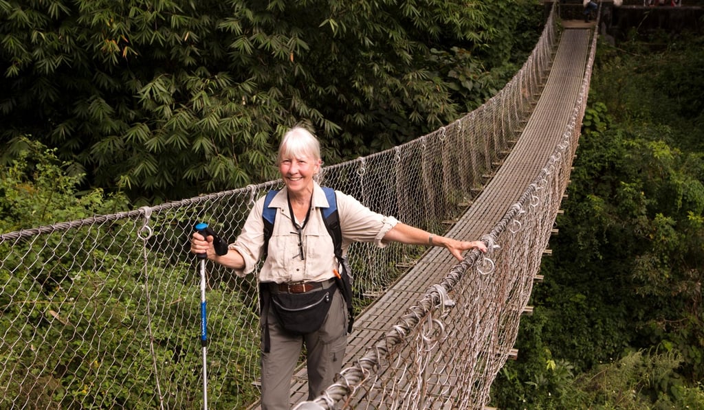 An older traveller pauses on a metal suspension bridge on the way from Pokhara to Tikhedungha in Nepal. Photo: Alamy