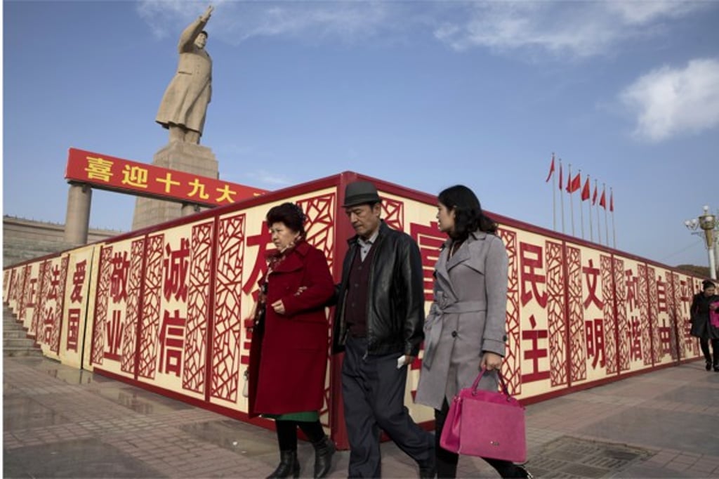 Residents walk past a statue of Mao Zedong near billboards saying “Welcome 19th congress”, “Patriotism” and “Democracy” in Kashgar. Photo: AP Residents walk past a statue of Mao Zedong near billboards saying “Welcome 19th congress”, “Patriotism” and “Democracy” in Kashgar. Photo: AP