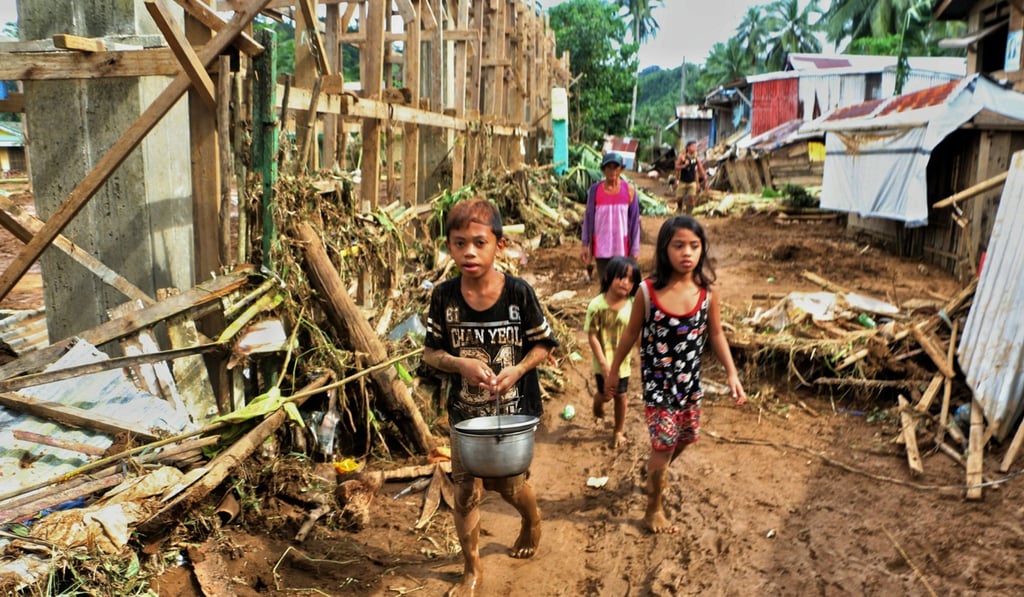 Children walk past debris and damaged houses in San Mateo Borongan in eastern Samar. Photo: AFP
