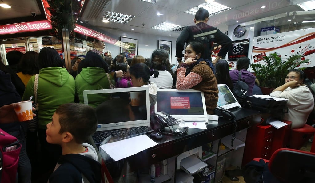 Domestic helpers and customers wait at Peya Travel in Central after air tickets could not be confirmed online. Photo: David Wong