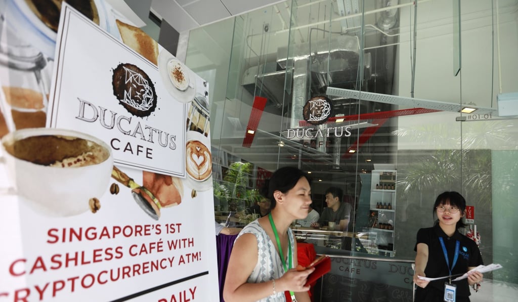 A staff member hands out brochures outside Ducatus cafe, which claims to be Singapore's first cashless cafe that accepts cryptocurrencies such as bitcoin, in the Central Business District of Singapore, on December 22, 2017. Photo: EPA-EFE
