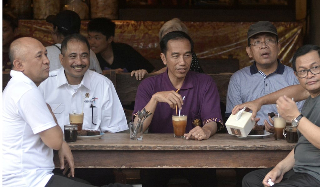 Indonesia President Joko Widodo, centre, sits with his ministers while visiting a cafe in Kuta Beach in Bali. Photo: Reuters