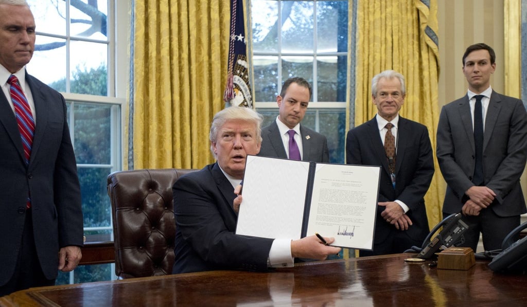 US Donald Trump holds up an executive order withdrawing the US from the Trans-Pacific Partnership in the Oval Office of the White House on January 23. Photo: Bloomberg