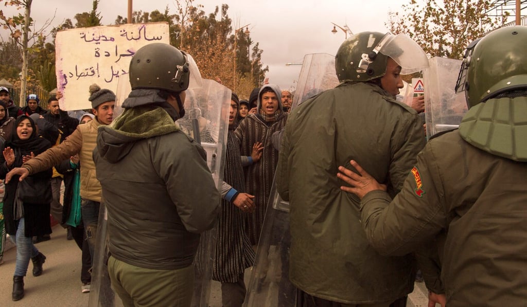 Anti-riot police stand guard as Moroccans shout slogans on Wednesday during a demonstration after the funeral of two brothers who died while digging in an abandoned coal mine in the northeastern city of Jerada. Photo: Agence France-Presse