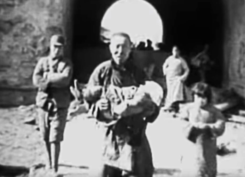 A man carries the body of a dead child in Nanking after bombing by the Japanese forces.