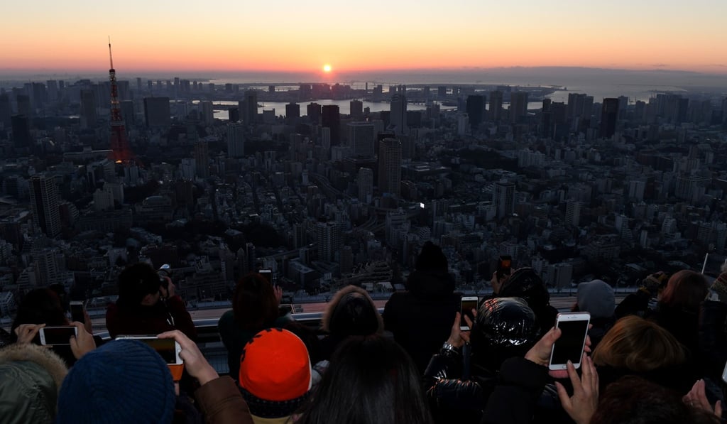 People take pictures as the sun rises over Tokyo Bay to mark New Year's Day on January 1, 2018. Photo: AFP