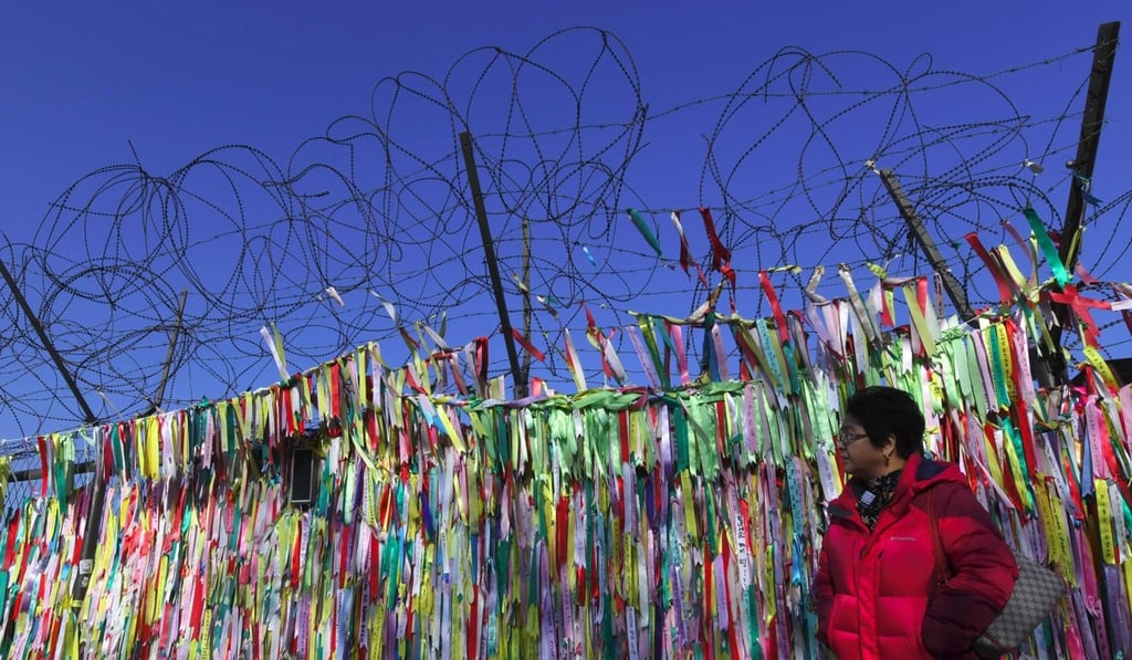 A woman walks past a military fence covered with ribbons calling for peace and reunification at the Imjingak Peace Park near the Demilitarized Zone dividing the two Koreas in the South Korean border city of Paju. Photo: AFP