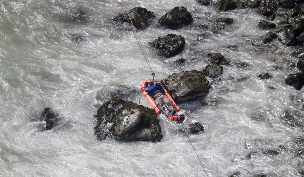 An injured man is transported over water from the scene of Tuesday’s bus accident north of Lima. Photo: AP