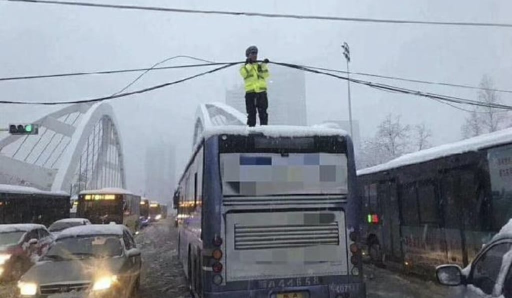 A traffic police officer holds up a fallen power cable in Hefei. Photo: China.com