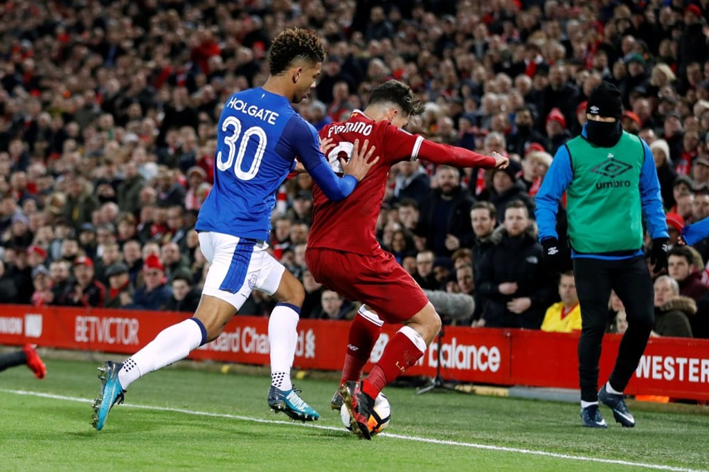 Roberto Firmino is pushed by Mason Holgate into the stands. Photo: Reuters