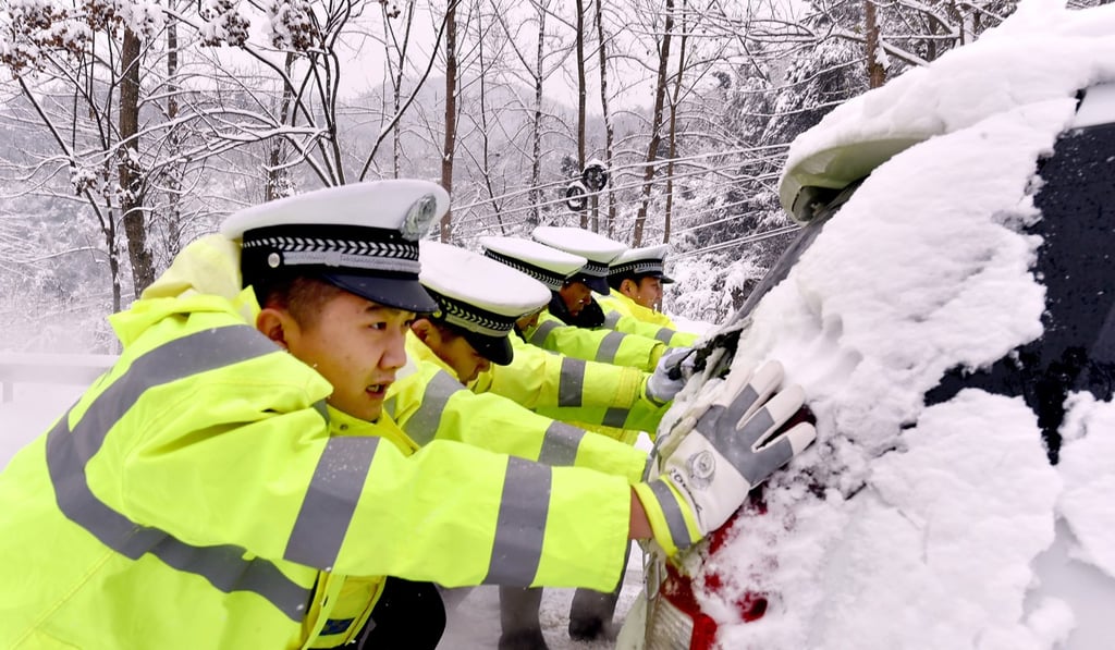 Traffic police officers push a car on a snow-covered road in Nanzhang county, in Hubei province. Photo: Xinhua Traffic police officers push a car on a snow-covered road in Nanzhang county, in Hubei province. Photo: Xinhua