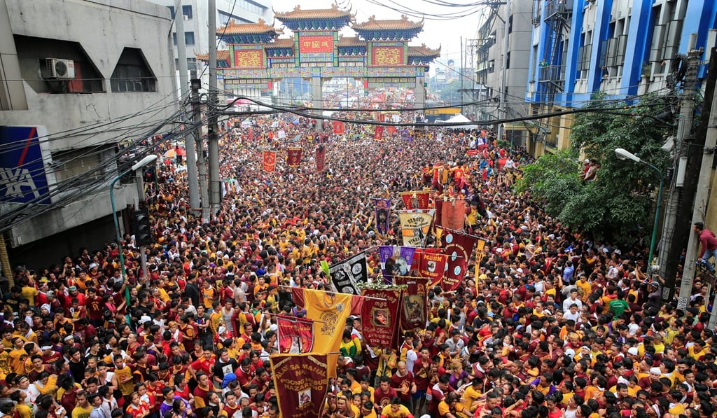 Devotees carry banners while others jostle to reach the carriage of the Black Nazarene during the annual procession in Manila. Photo: Reuters