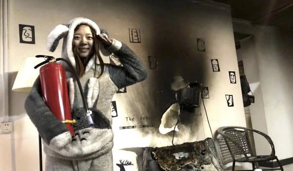 One of the couple poses with a fire extinguisher with some of the damage shown from the blaze. Photo: Sohu.com