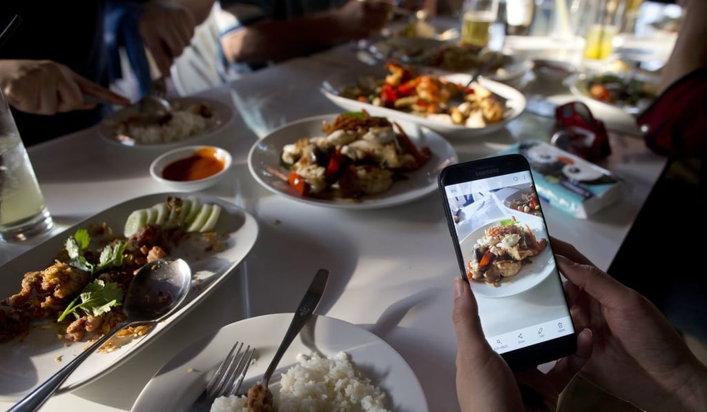 A customer takes photos of food cooked by Thai cook Supinya Jansuta. Photo: AP A customer takes photos of food cooked by Thai cook Supinya Jansuta. Photo: AP