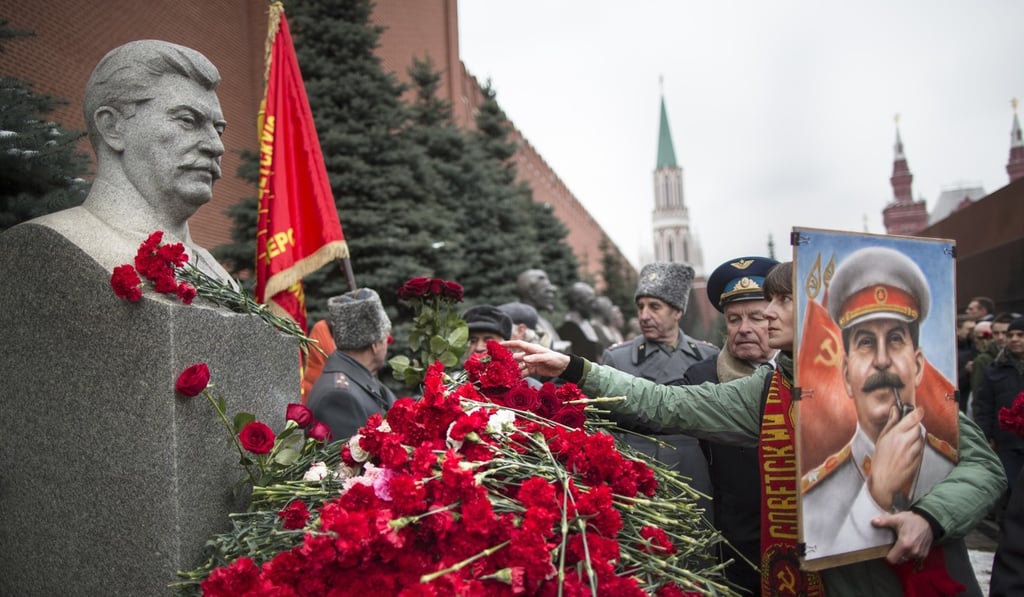 A woman holding a portrait of Stalin places flowers near the monument of Joseph Stalin's grave near the Kremlin wall marking the anniversary of Stalin's birth in Moscow's Red Square, on December 21, 2017. Photo: AP