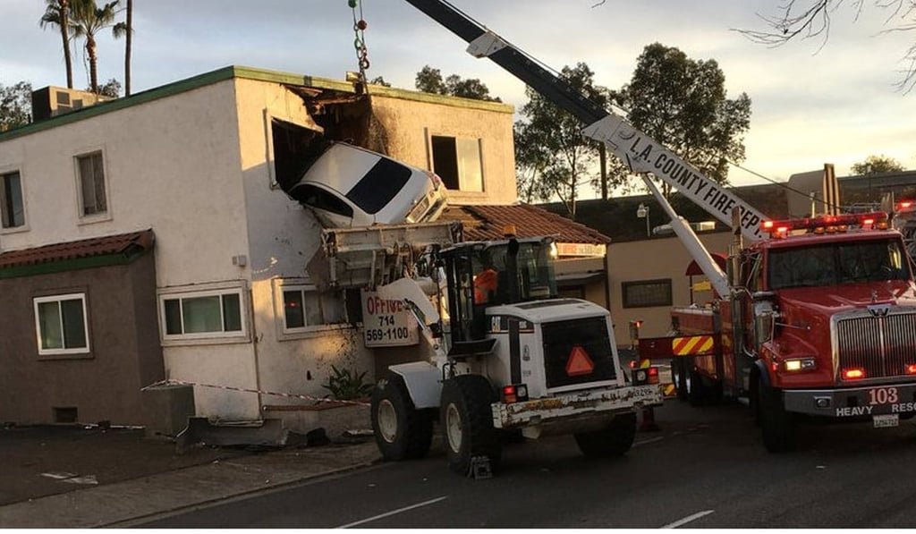 Rescuers extract a car that crashed into a building after speeding into a median and going airborne in Santa Ana, California, on Sunday. Photo: Reuters