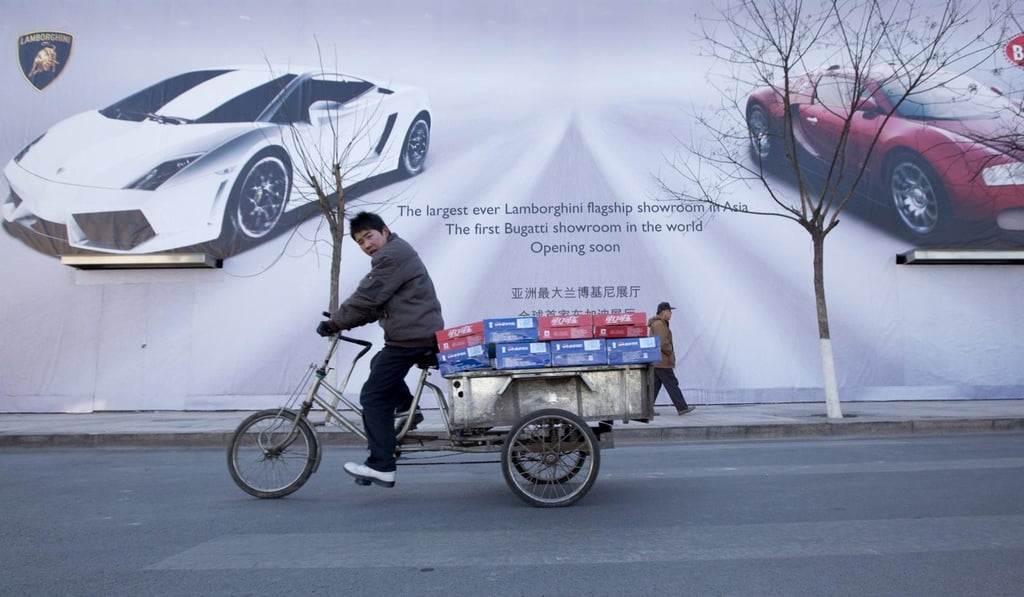 A cyclist passes an advertisement for a soon-to-be opened showroom for Bugatti and Lamborghini supercars in Beijing. While the wealth gap between nations is declining partly due to the rise of China, stark inequality persists within the country. Photo: EPA