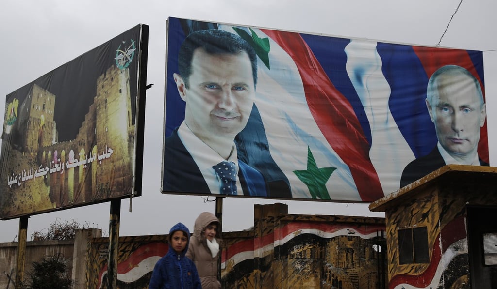 Syrian walk by posters of Syrian President Bashar al-Assad and Russian President Vladimir Putin in Aleppo, Syria. Photo: AP