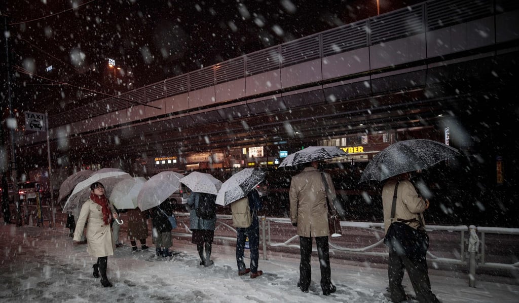 People wait in a queue for taxis at Akihabara station during a snowfall in Tokyo. Photo: AFP