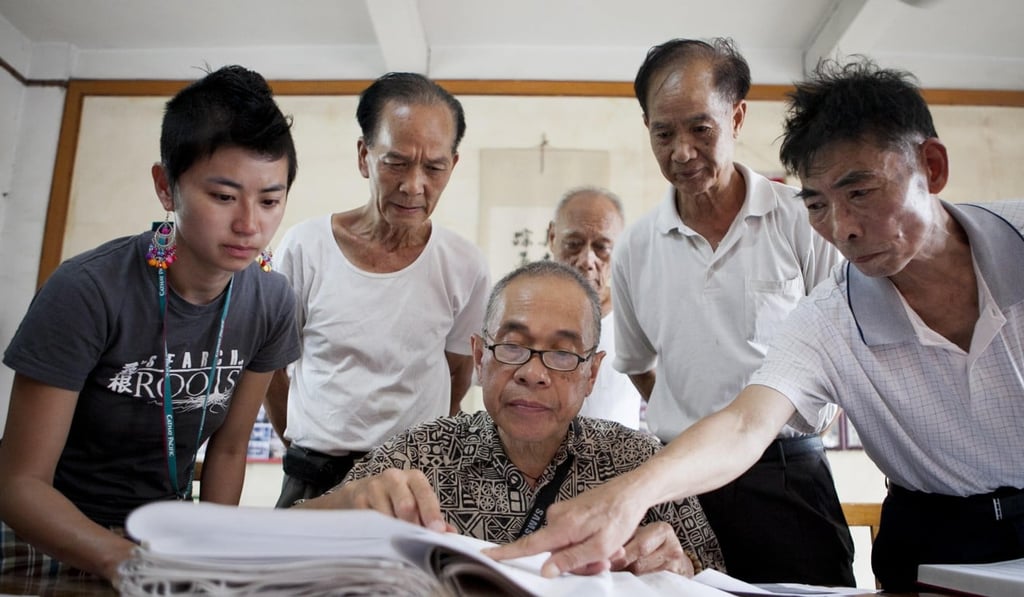 Albert Cheng (centre), the fourth generation Chinese-American who runs Friends of Roots, helps a young group member search village archives. Photo: courtesy of Albert Cheng