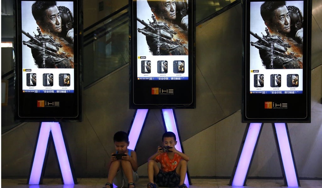 Children use smartphones at a cinema in Beijing. The technology’s inbuilt addictiveness makes it hard for children to choose other activities such as reading. Photo: AP