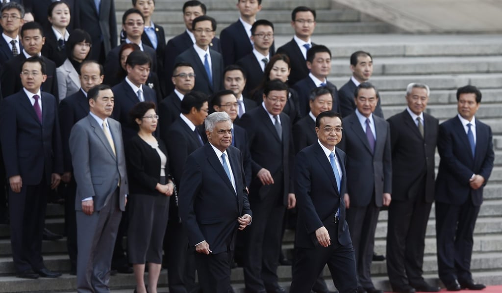 Sri Lankan Prime Minister Ranil Wickremesinghe and Chinese Premier Li Keqiang walk past the Chinese delegation during a welcome ceremony at the Great Hall of the People in Beijing in April 2016. Sri Lanka has benefited from Chinese development financing in recent years but some are questioning whether the price tag is too high. Photo: EPA