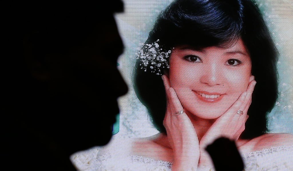 A man holds a rose in front of Teresa Teng's picture during memorial service to commemorate the 62nd birthday of the late pop singer Teresa Teng. Photo: Nora Tam