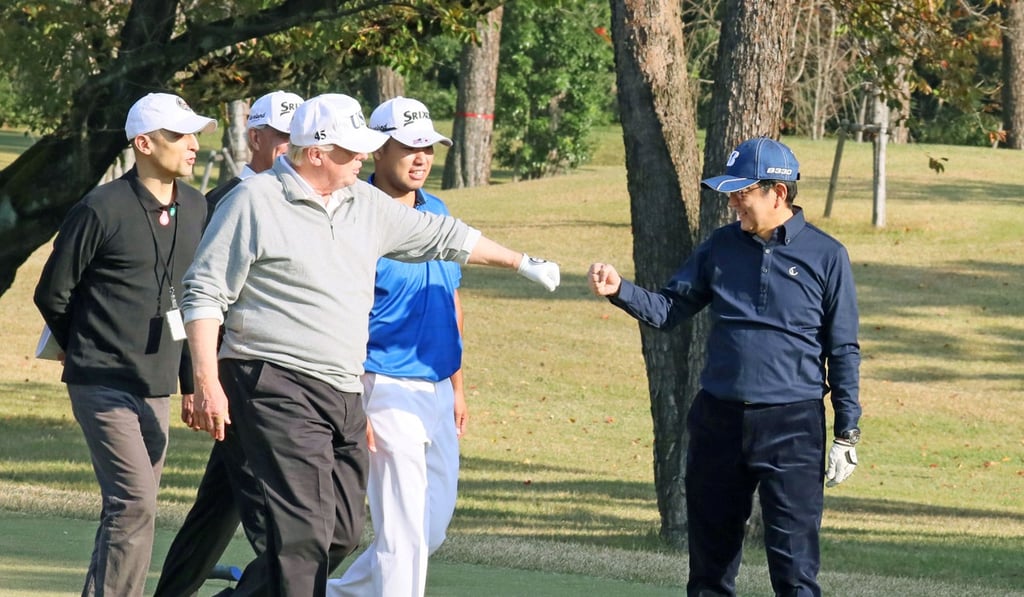 US. President Donald Trump fist bumps Japan’s Prime Minister Shinzo Abe as Japanese professional golfer Hideki Matsuyama looks on, as they play golf at the Kasumigaseki Country Club in Kawagoe, north of Tokyo, on November 5, 2017. Photo: Kyodo