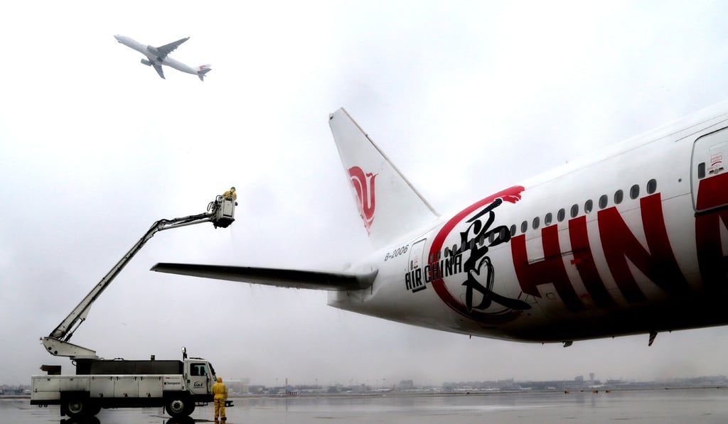 Ground staff members remove ice and snow on a plane at Hongqiao International Airport in Shanghai. Photo: Xinhua