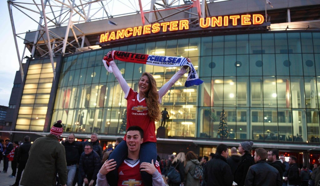 Manchester United fans pose for photographs in front of Old Trafford stadium before an English Premier League game. Photo: AFP