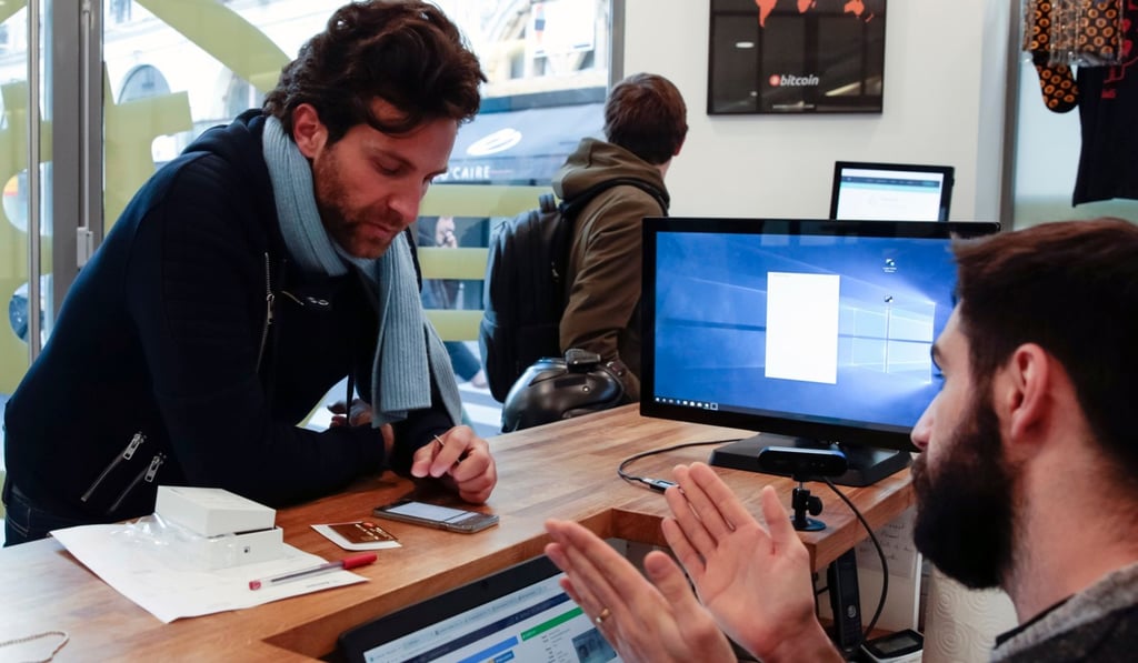 A man stands at a desk at La Maison du Bitcoin in Paris on January 17, 2018 to buy digital bitcoin. Photo: AFP