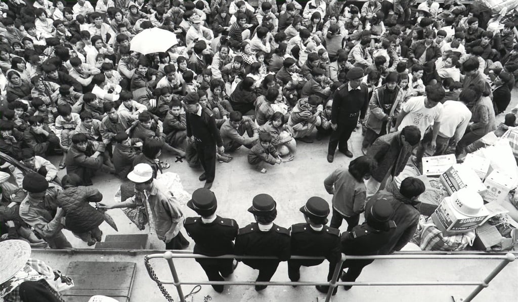 Marine police guarding a group of northern Vietnamese boatpeople, while they wait to move with their belongings to Hei Ling Chau following the 1992 fire. Picture: SCMP