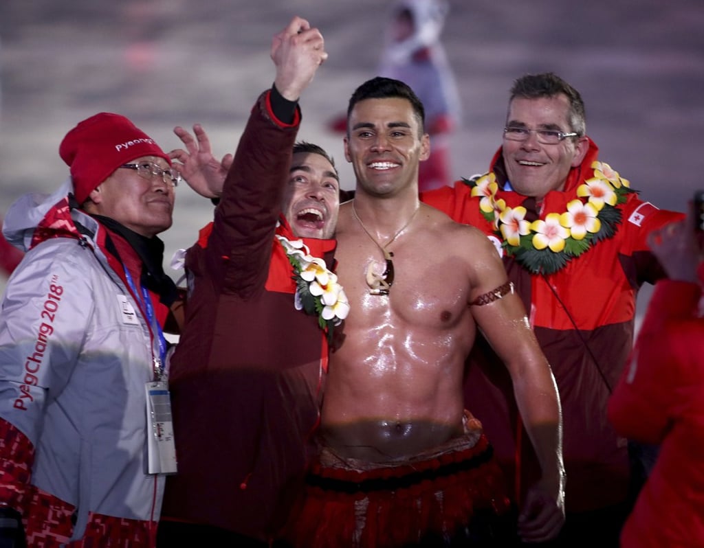 Tonga flag bearer Pita Taufatofua poses with a volunteer and teammates during the opening ceremony. Photo: AP