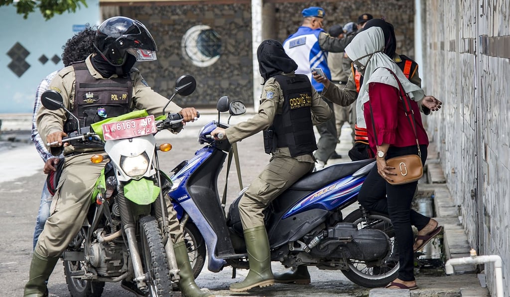 Police officers detain unmarried couples after a raid at a hotel in Surabaya, Indonesia on Valentine’s Day. Photo: AFP