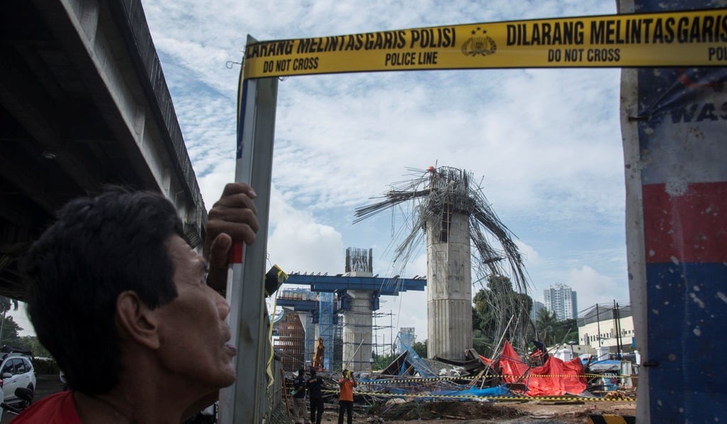 A man stands near a collapsed girder pole on the construction site of the Bekasi-Cawang toll overpass in Jakarta, Indonesia. Photo: Reuters
