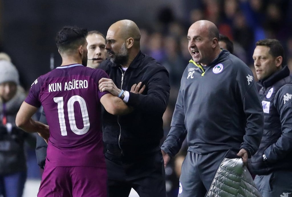 Manchester City manager Pep Guardiola restrains Sergio Aguero while Wigan Athletic manager Paul Cook looks on after Fabian Delph was shown a red card. Photo: Reuters